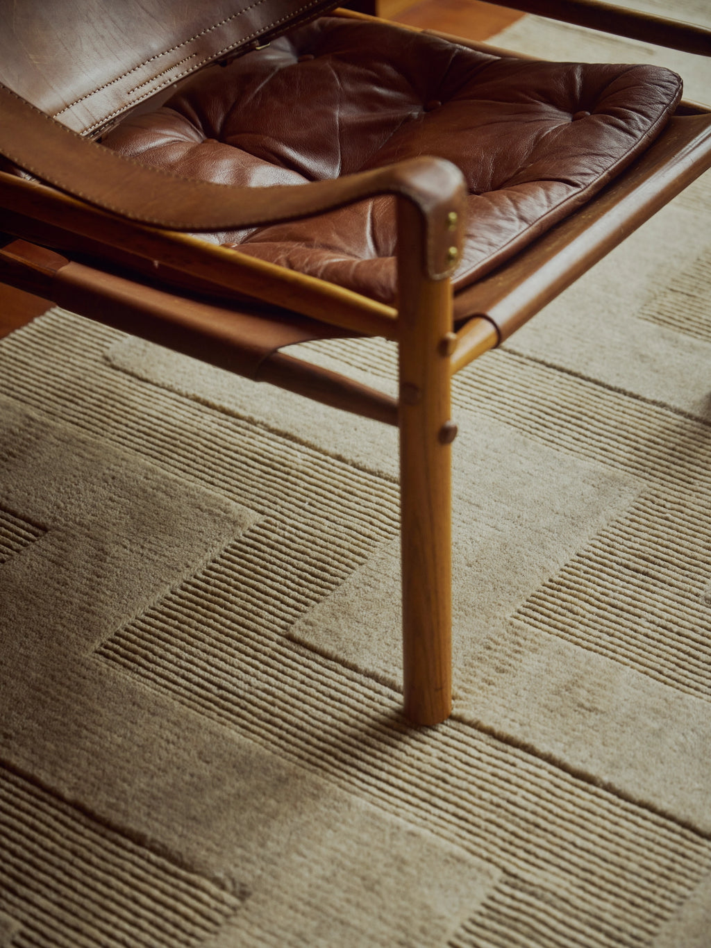 Tinted Objects Valmont Wool Rug, a premium light beige area rug with a textured, geometric striped pattern. This durable, stylish wool rug is perfect for adding warmth and modern design to contemporary living spaces.
