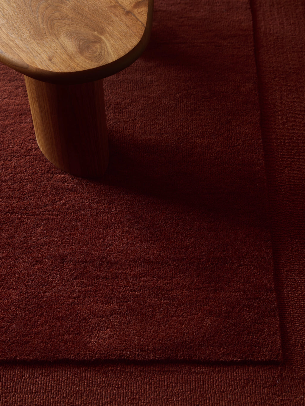 Tinted Objects Louis Wool Rug, a luxurious deep red area rug with a subtle textured pile. This premium wool rug adds warmth and sophisticated style, ideal for modern living rooms or cozy bedrooms.