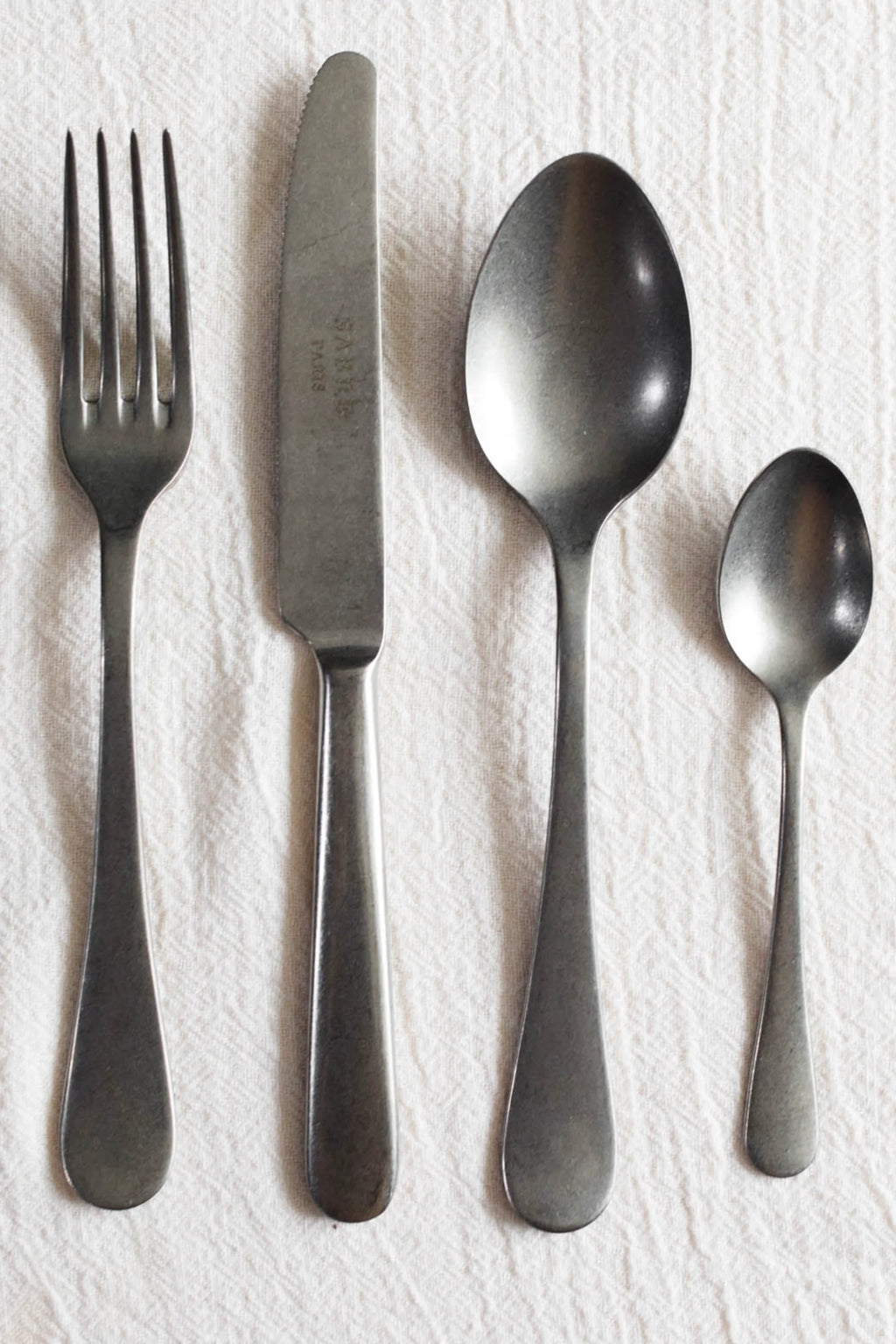 Sabre Paris Marius 5-Piece Cutlery Flatware Set, featuring a modern, brushed gunmetal finish on durable stainless steel, including a fork, knife, dinner spoon, and teaspoon. This stylish flatware set is perfect for contemporary dining rooms and home entertaining.