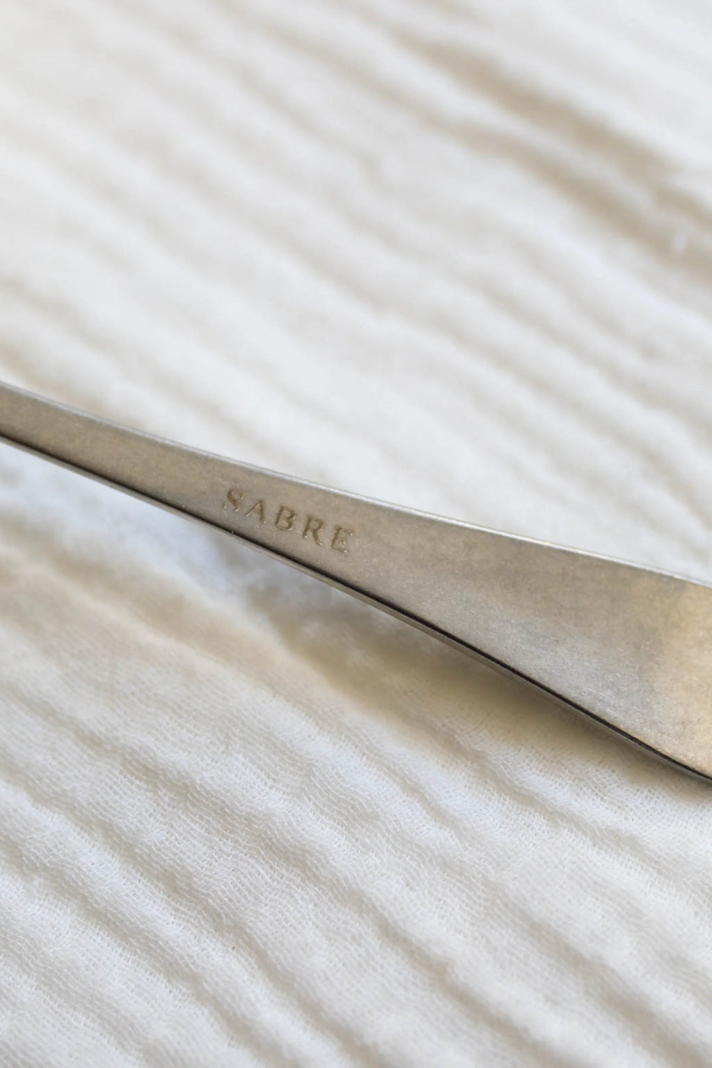 Sabre Paris Marius 5-Piece Cutlery Flatware Set, featuring a sleek, brushed stainless steel handle with the "SABRE" logo engraved. This durable, modern flatware is perfect for contemporary dining rooms and stylish home entertainers.