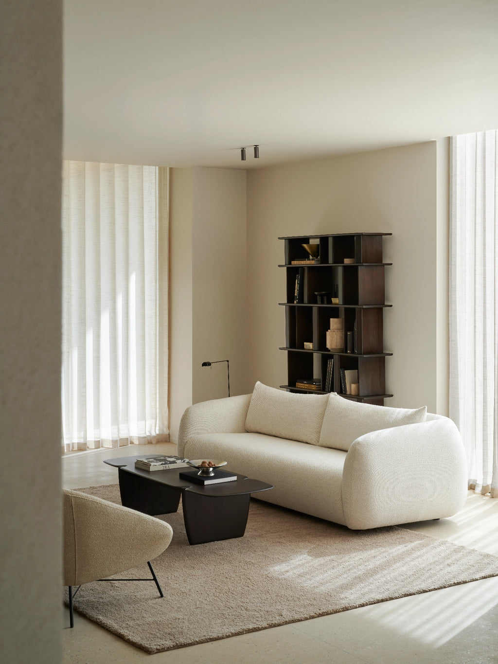 Ethnicraft Figur Sofa, a contemporary organic modern sofa featuring a distinct curved, sculptural silhouette upholstered in a textured cream bouclé fabric with plush seating and rounded armrests. This minimalist off-white sofa is perfect for a stylish living room or an inviting contemporary lounge space.