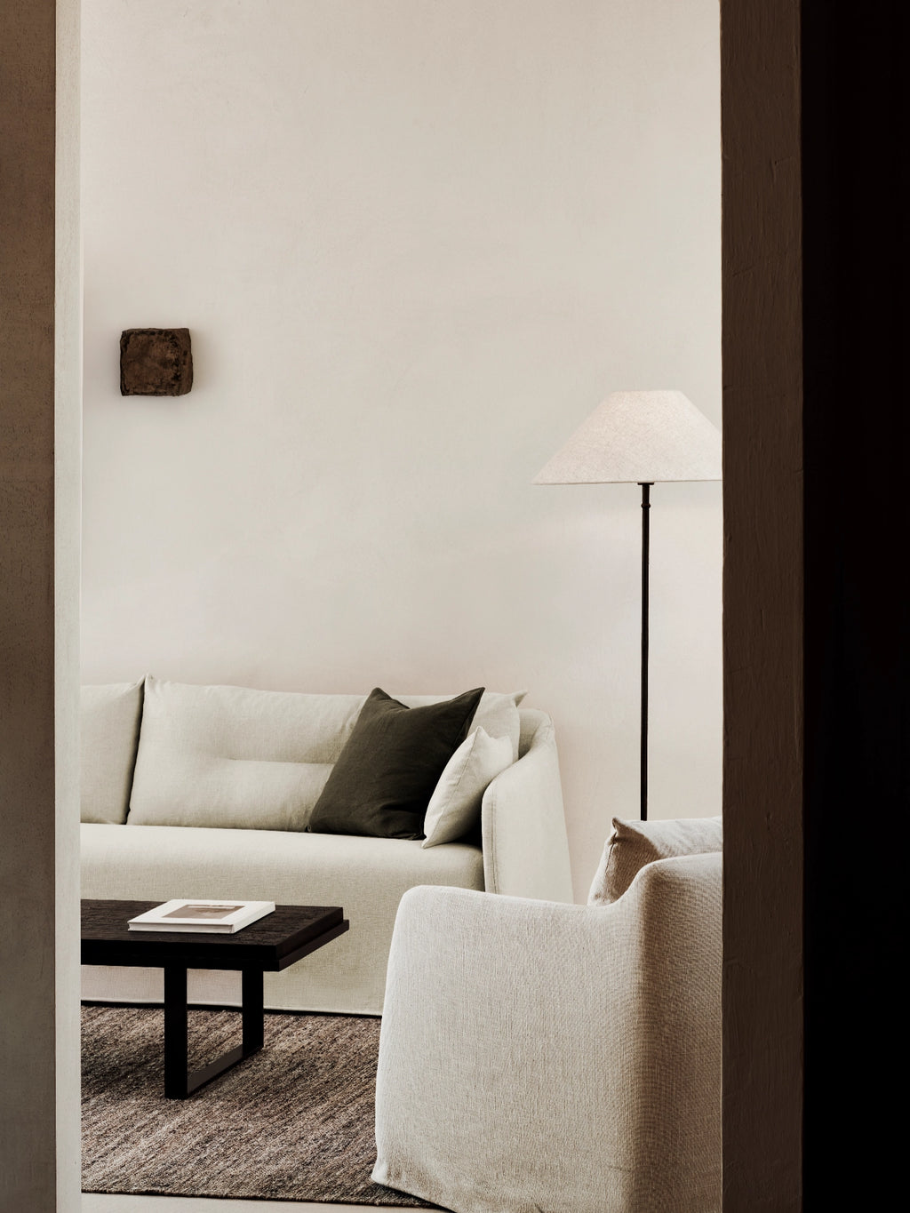 Ethnicraft Weave Sofa, a modern minimalist sofa featuring plush, textured natural linen-blend upholstery in a light beige or off-white hue, offering deep seating and clean lines. Accented with a dark olive green throw pillow, this contemporary couch is perfect for organic modern living rooms and serene, design-conscious interiors.