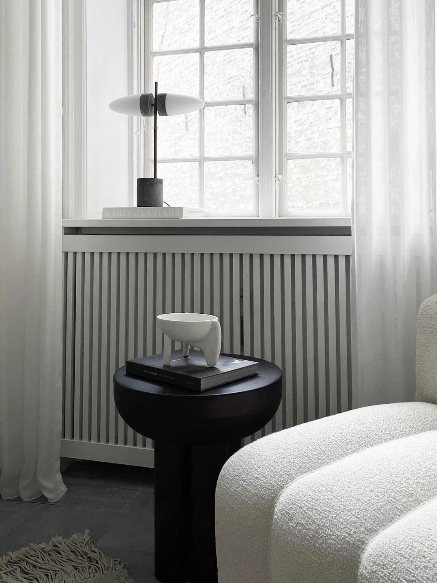 101 CPH Crown Side Table. A luxurious, dark solid wood side table in a modern living space next to a white bouclé couch. Perfect for sophisticated décor.