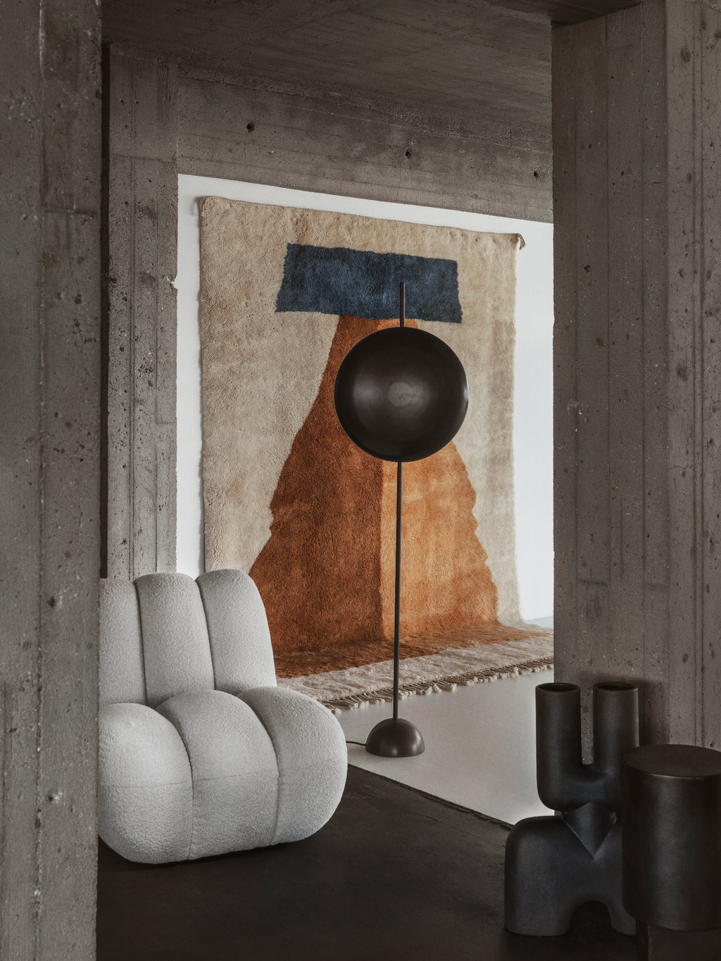 101 CPH Totem Floor Lamp: A modern black spherical lamp with a tall slender stand and circular base, positioned in a contemporary living space. This sculptural lighting piece offers a minimalist design.