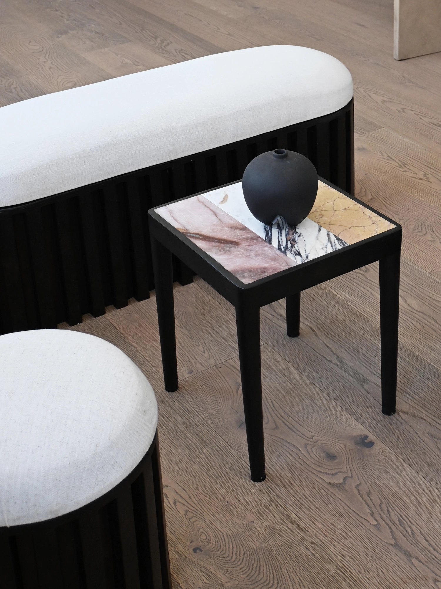 101 CPH Tairu Table, a luxury square side table with a unique multicolor honed marble top in white, rose, and amber tones, on a black metal base. Ideal as a premium decorative accent.
