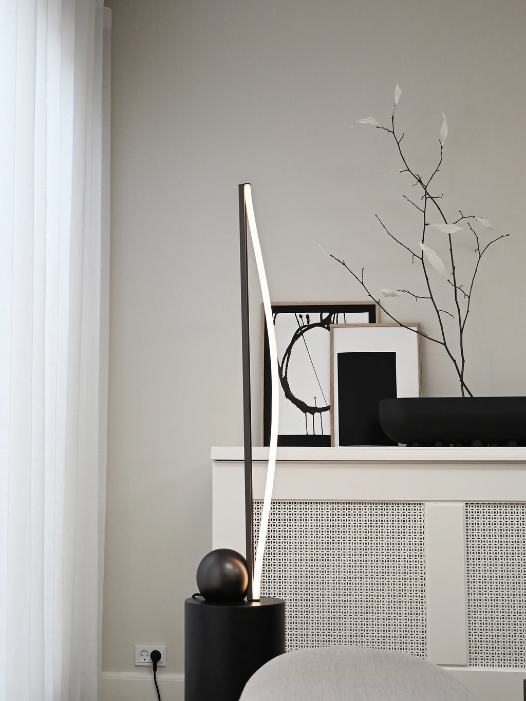 101 CPH Bow Floor Lamp, a modern matte black cylinder base supporting a sleek arching lamp with a bright LED strip, showcased in a minimalist living room. Creates premium ambient lighting.