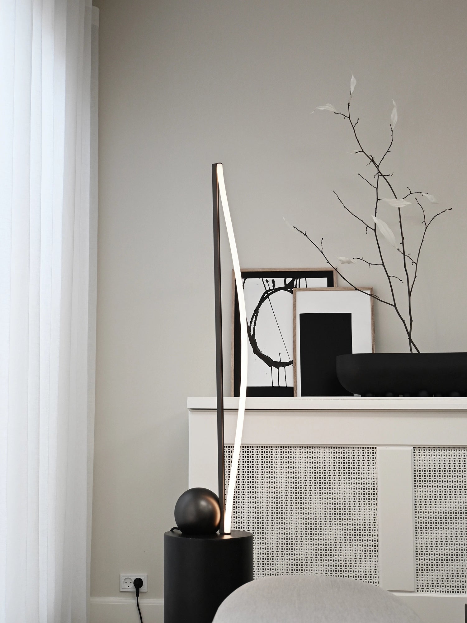 101 CPH Bow Floor Lamp, a modern matte black cylinder base supporting a sleek arching lamp with a bright LED strip, showcased in a minimalist living room. Creates premium ambient lighting.