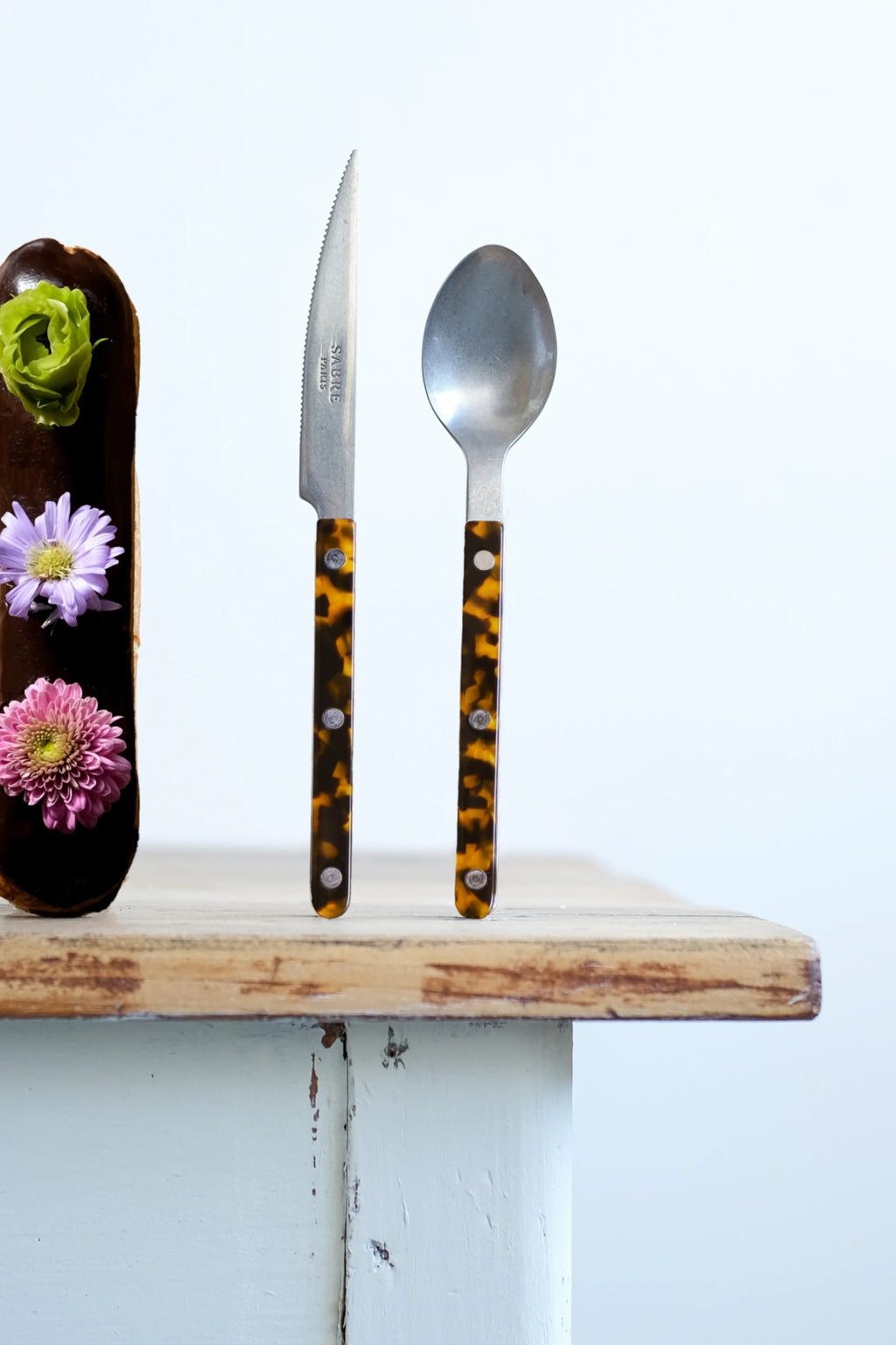 Sabre Paris Bistrot Vintage Tortoise 4-Piece Cutlery Flatware Set, featuring a knife and spoon with glossy, mottled tortoise shell-patterned handles and silver-toned stainless steel heads. This stylish flatware set is perfect for enhancing elegant dining experiences for those who appreciate vintage aesthetics.