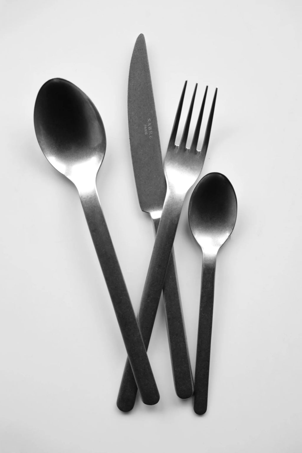 Sabre Paris Loft Vintage Cutlery Set, featuring a modern matte black finish on durable stainless steel utensils, including a dinner fork, dinner knife, and two spoons. This stylish flatware set is perfect for contemporary dining rooms and individuals seeking unique, high-quality tableware.