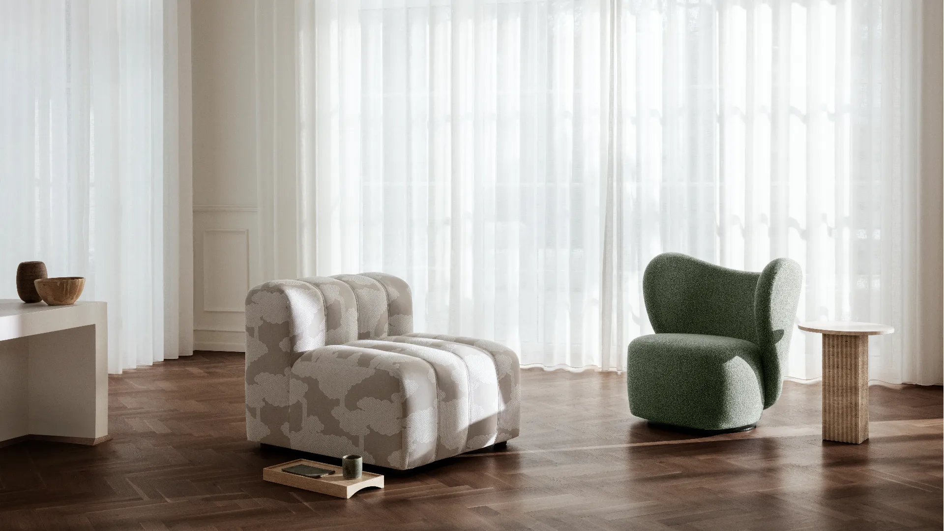Modern living room with a patterned armchair and a green chair against a white curtain backdrop.