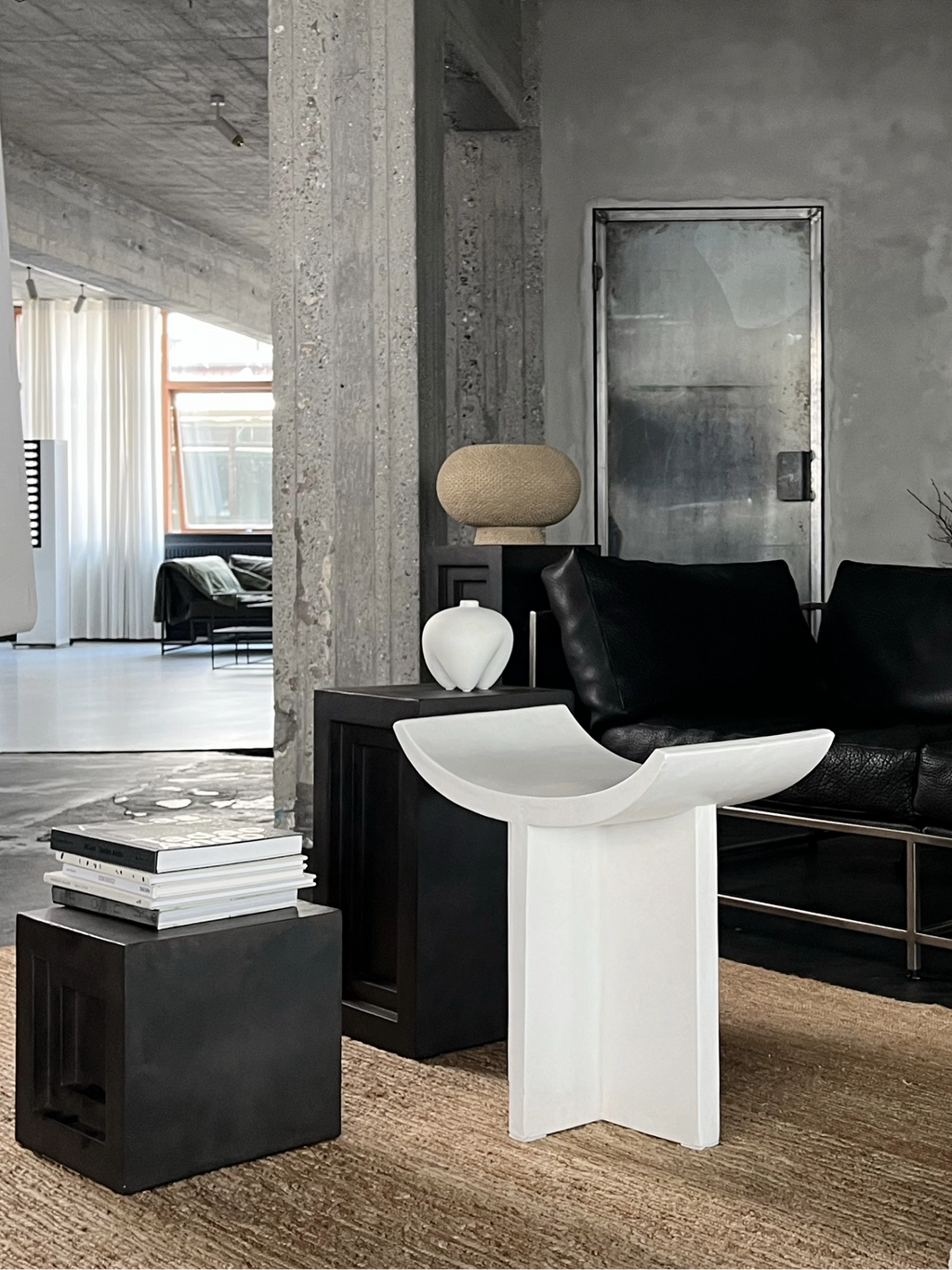 101 CPH Kabin Vase - Shisen: White sculptural stoneware vase with fluted details, displayed as an elegant accent next to a black sofa on a textured rug. A premium decorative piece for modern interiors.