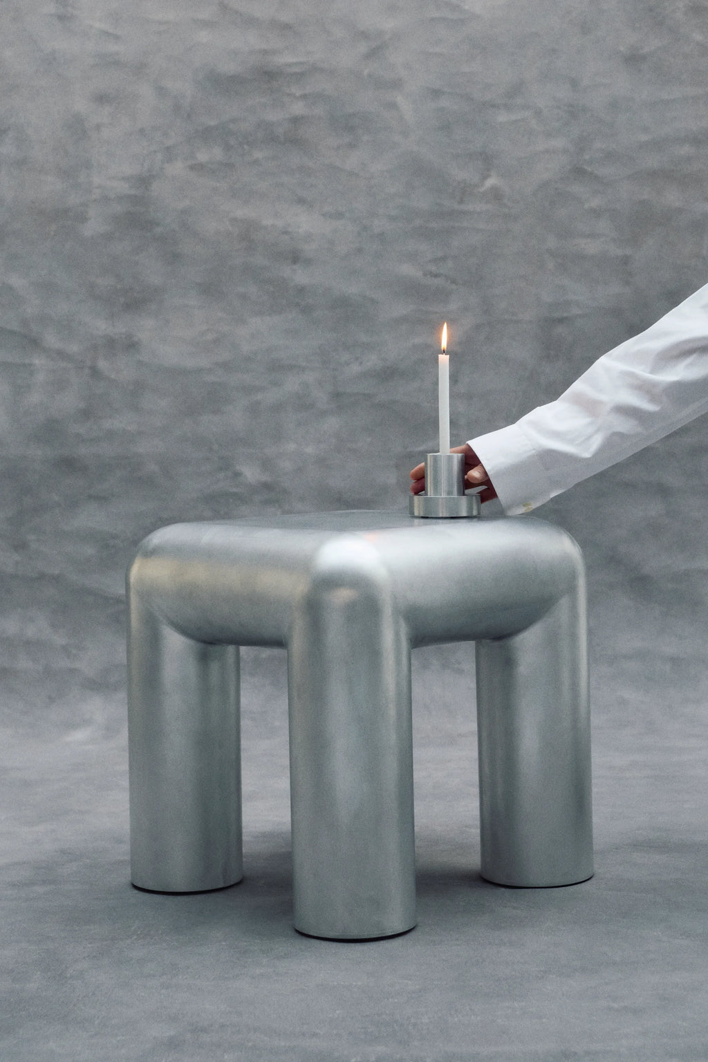 Metallic stool with a candle on a gray background