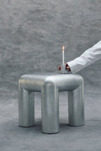 Metallic stool with a candle on a gray background