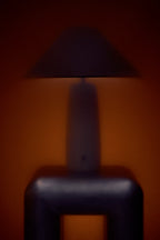 Dark lampshade casting a shadow on a wall