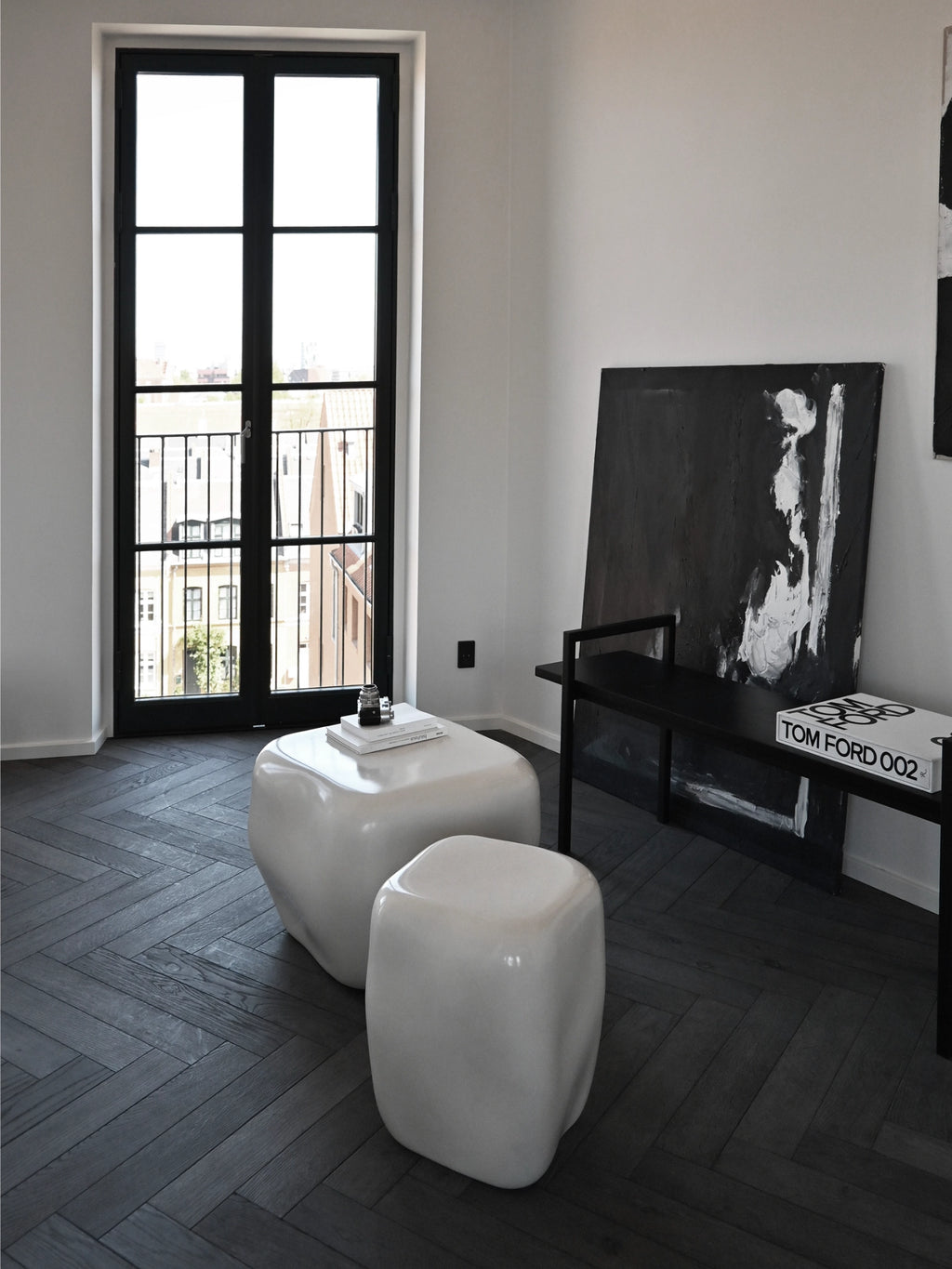 101 CPH Ishi Coffee Table - Ceramic collection, featuring two organic-shaped, glossy white ceramic tables on a dark chevron floor in a minimalist room. Ideal for modern living spaces.