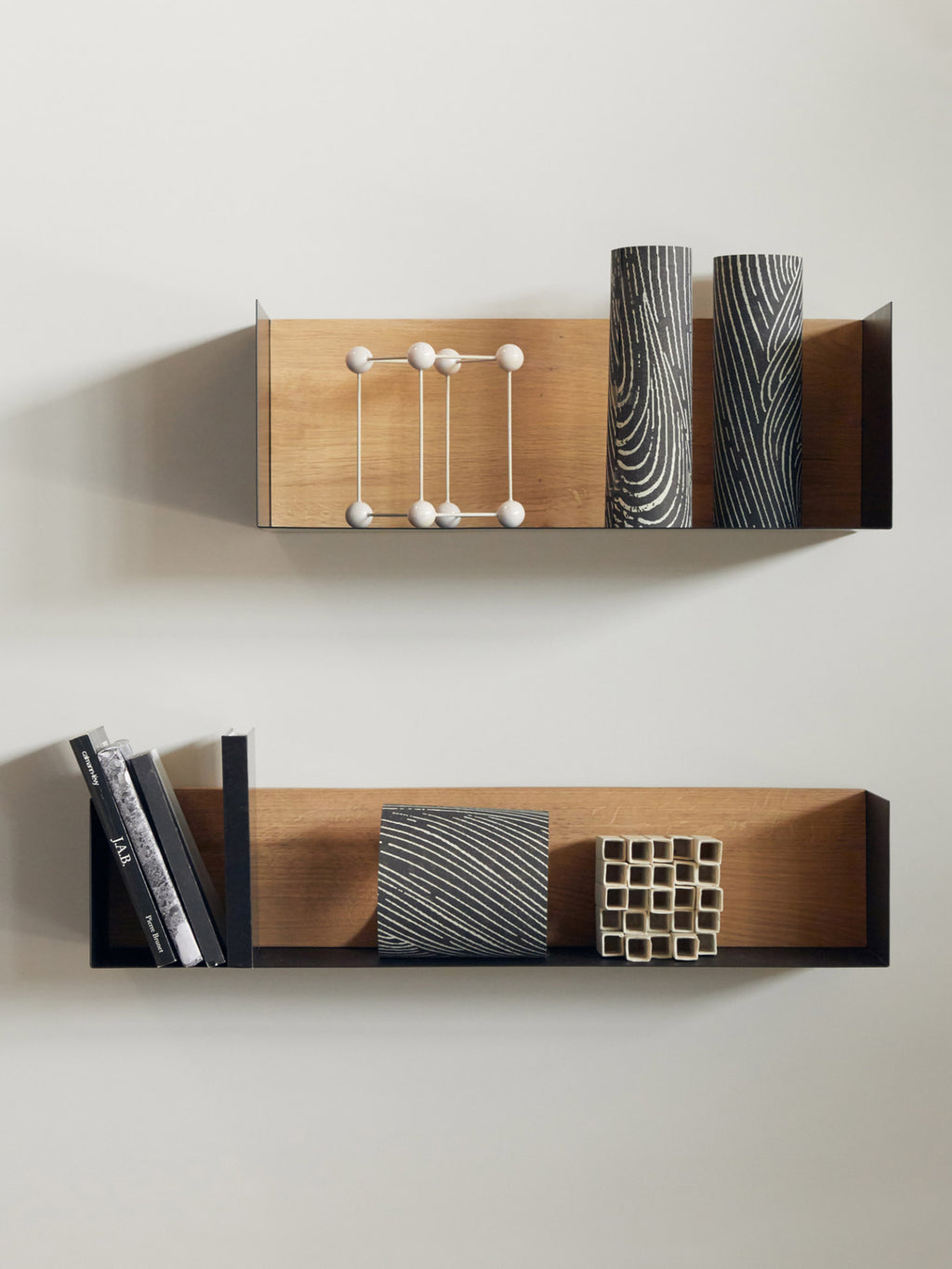 Ethnicraft U Shelf, a sleek modern wall shelf crafted from solid natural oak with a contrasting matte black metal U-shaped frame. This minimalist floating shelf offers a contemporary display solution with clean lines, perfect for Scandinavian or industrial-chic interiors. Ideal for living rooms, home offices, or bedrooms seeking stylish and functional wall storage.