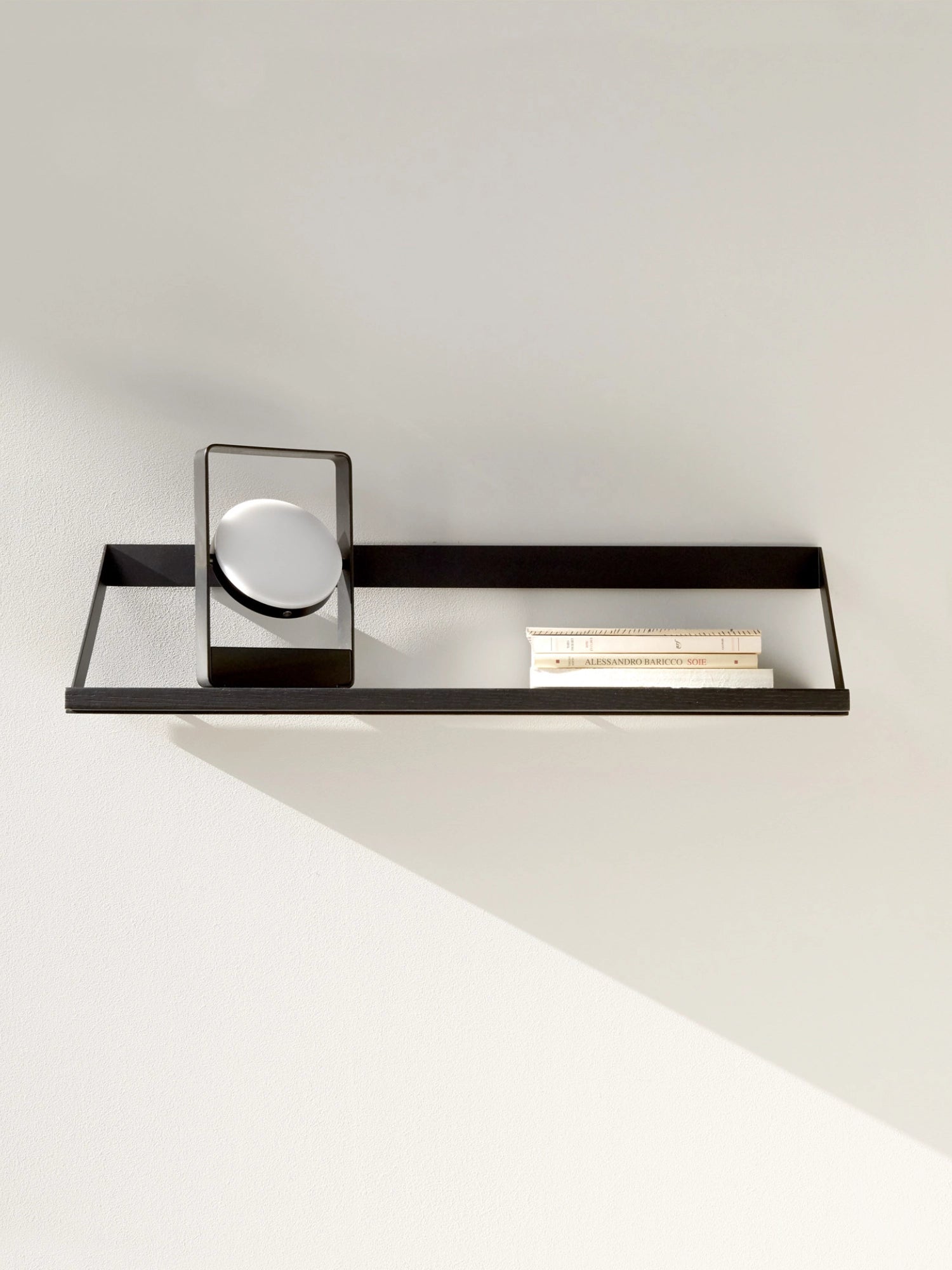 Ethnicraft Ribbon Shelf, a sleek modern minimalist floating wall shelf featuring a dark stained solid oak wood surface framed by a distinctive matte black metal structure with angled supports. This contemporary rectangular shelf provides elegant storage and display space for modern living rooms, minimalist bedrooms, or stylish home offices.