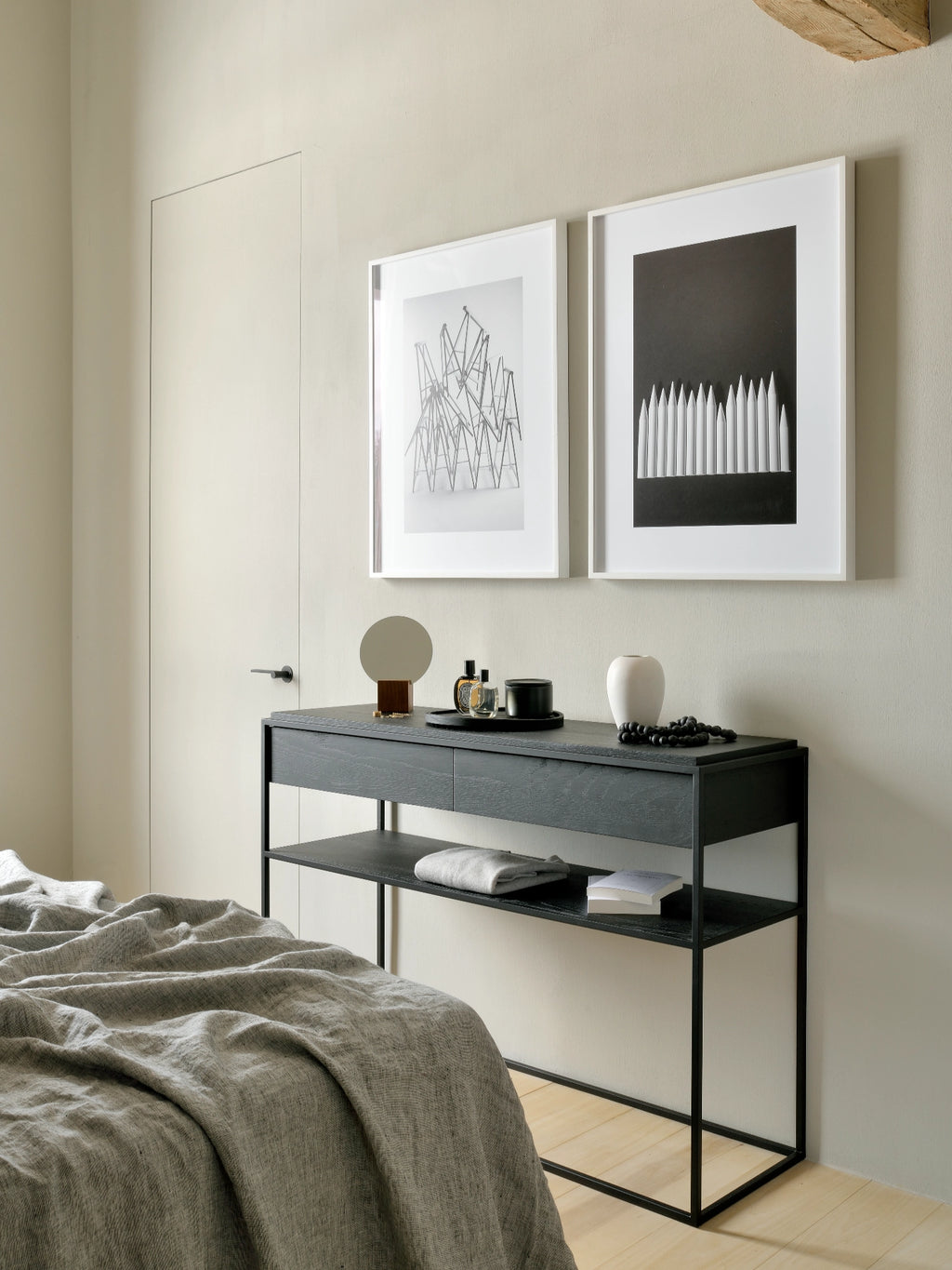 Ethnicraft Monolit Console, a sleek modern minimalist console table featuring a dark black stained oak top and open shelves with visible wood grain, supported by a slim matte black metal frame. This contemporary design includes a discreet integrated drawer and offers practical open storage. Ideal as a stylish console table for a modern bedroom, minimalist entryway, or sophisticated living room.