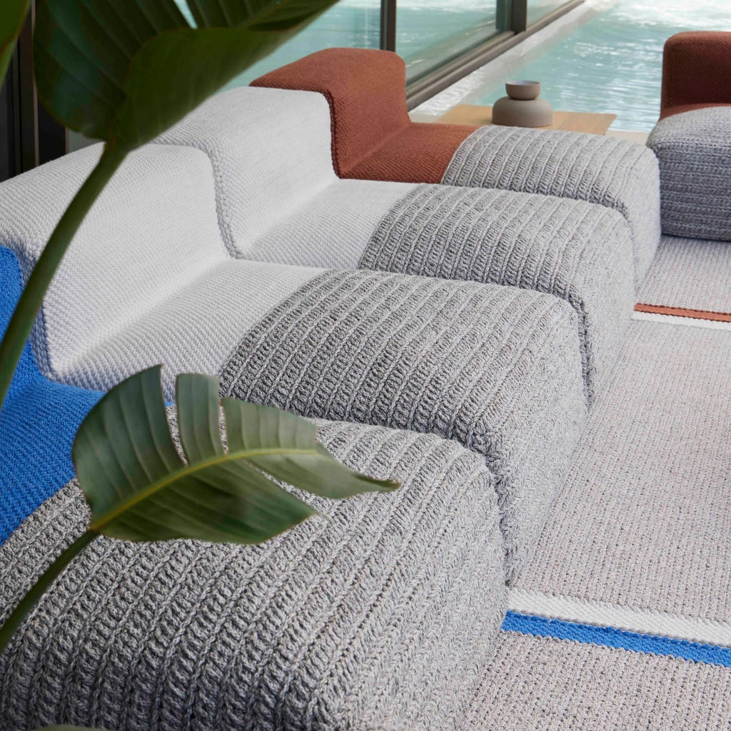 GAN Rugs Mangas Outdoor Composition 2, a contemporary modular outdoor sofa featuring a unique multi-textured design with chunky knitted light grey sections, smooth white woven accents, and vibrant royal blue and terracotta ribbed elements.