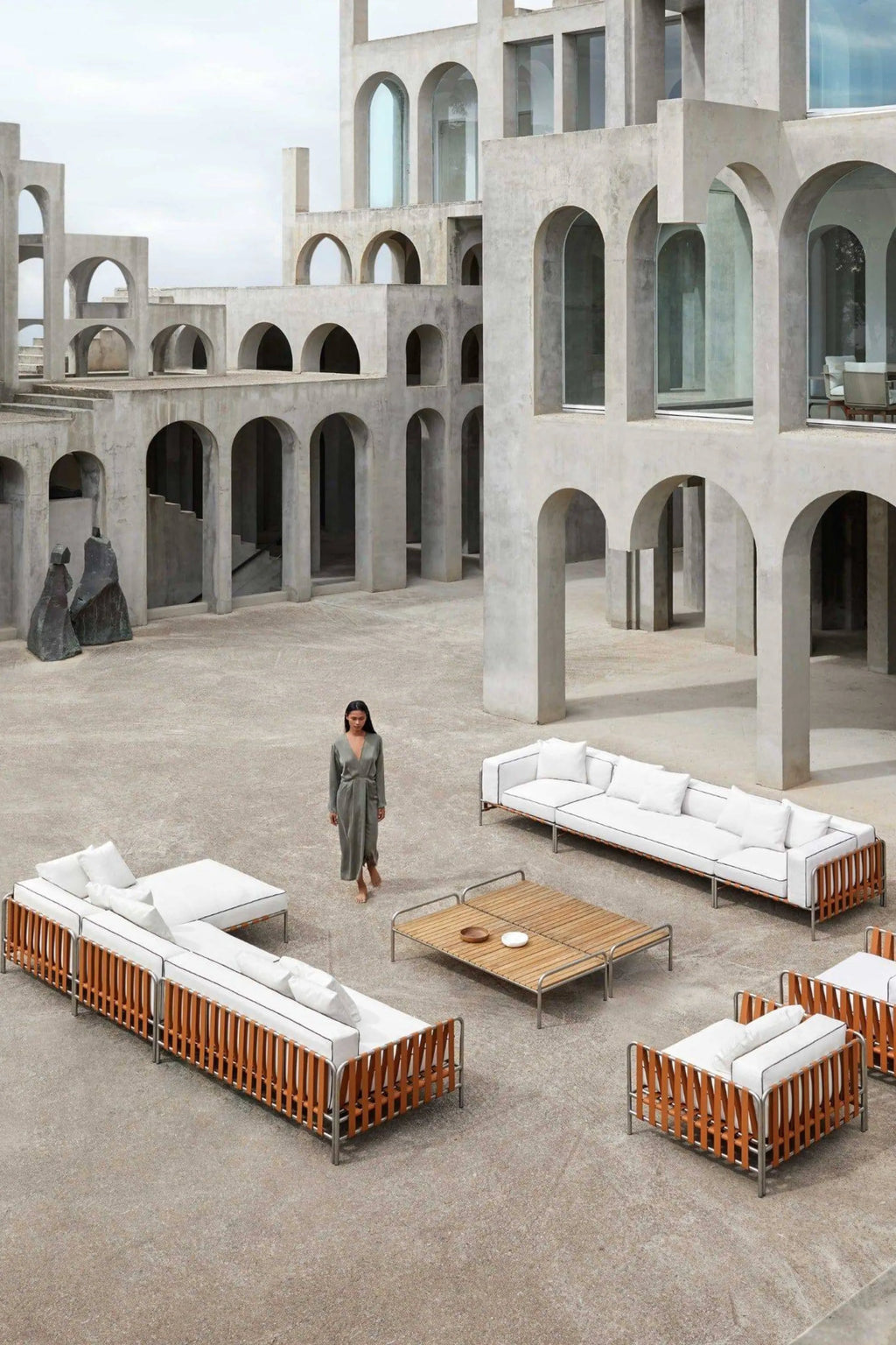 Gandia Blasco Onsen Sectional 6, a luxurious modular outdoor sofa featuring a sleek brushed stainless steel frame, warm cognac leather strap detailing, and plush white cushions with elegant black piping.