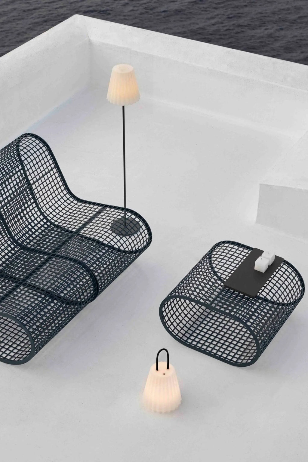 Gandia Blasco Buit Coffee Table, a modern outdoor coffee table crafted from dark grey coated aluminum with a distinctive grid mesh pattern and an oval shape. This contemporary patio lounge table features a removable matte black tabletop insert for serving, designed for both durability and style. Ideal for minimalist outdoor spaces, modern terraces, or chic poolside lounge areas.