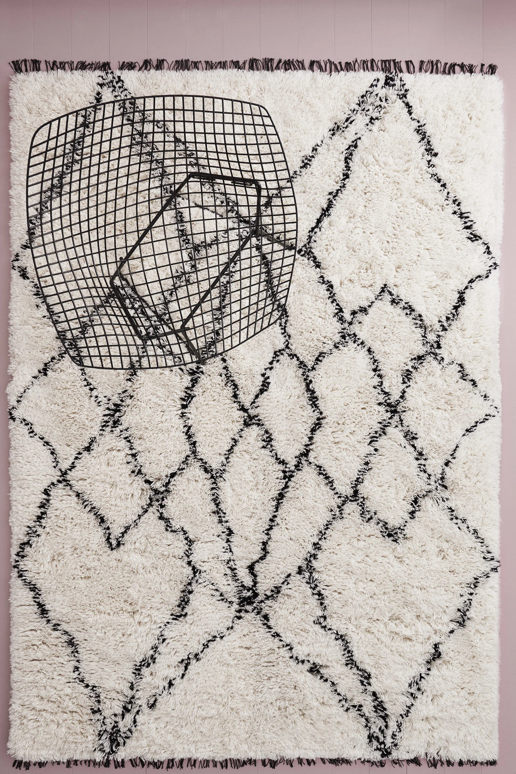 Linie Design Ruffle Wool Rug, a plush cream-colored shaggy wool area rug featuring a bold black diamond pattern and distinctive black fringed edges.