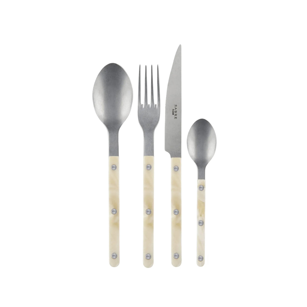 Sabre Paris Bistrot Horn Cutlery Set, featuring a fork, knife, dinner spoon, and tea spoon with elegant cream-colored, marbled horn-look handles and polished stainless steel. This stylish, durable cutlery set is perfect for enhancing everyday dining or special occasions for those who appreciate classic design.