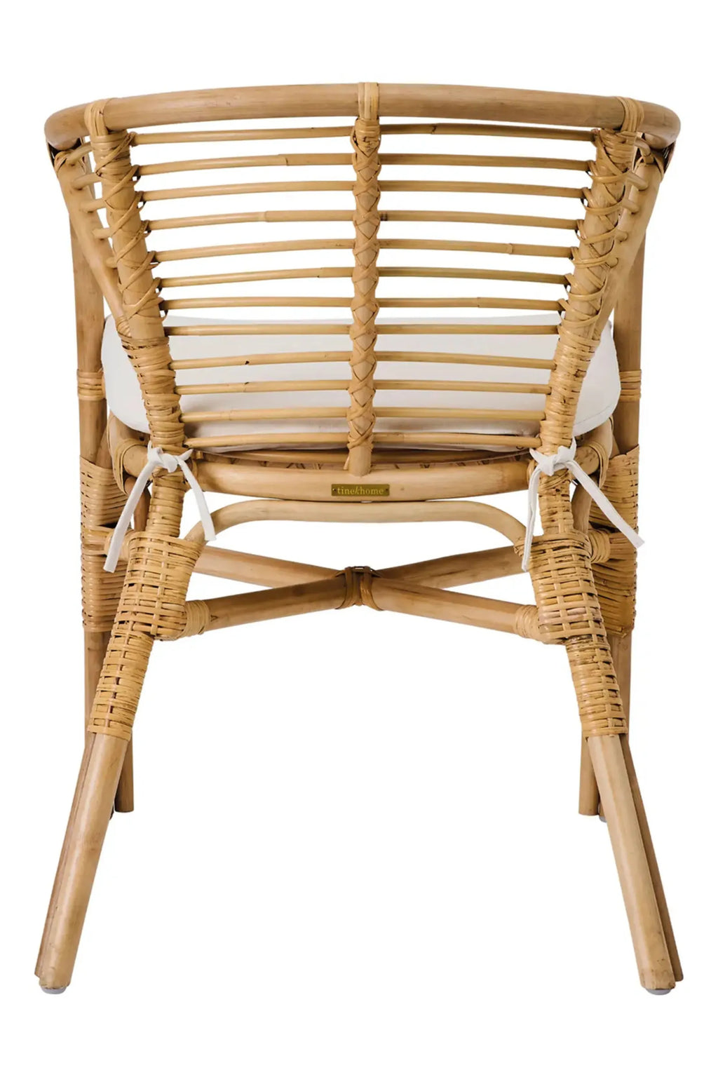 Tine K Dola Rattan Chair - Set of 2, a natural light brown rattan dining chair with a curved backrest featuring horizontal slats and intricate woven details on the frame and legs. This boho-inspired chair includes a comfortable white seat cushion and an X-shaped crossbar for stability, embodying an organic modern or coastal design style. Ideal as a stylish rattan dining chair for a relaxed kitchen, living room accent, or sunroom.
