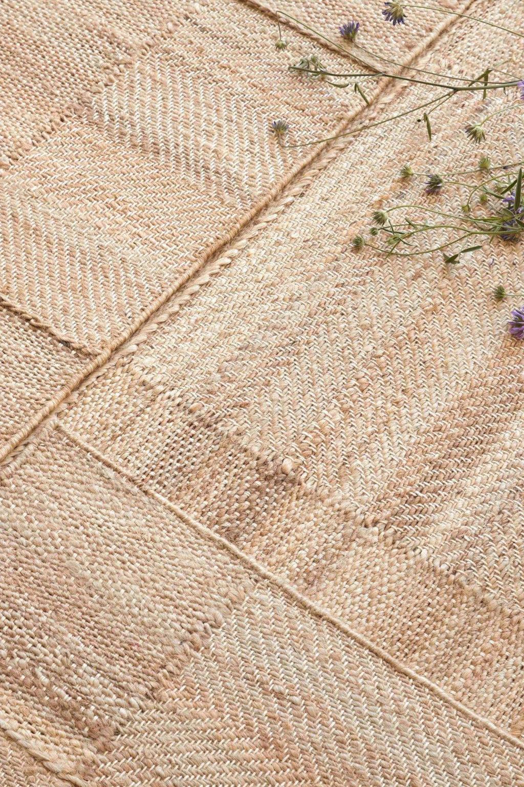 GAN Rugs Roots 02 Rug, a hand-woven natural fiber area rug in warm beige and cream tones, featuring a patchwork design of varying textures. It showcases intricate herringbone weaves and plainer sections, creating a rich, organic feel from its natural undyed fibers. This rustic, organic modern rug is perfect for grounding living rooms, bedrooms, or coastal and japandi-inspired interiors.