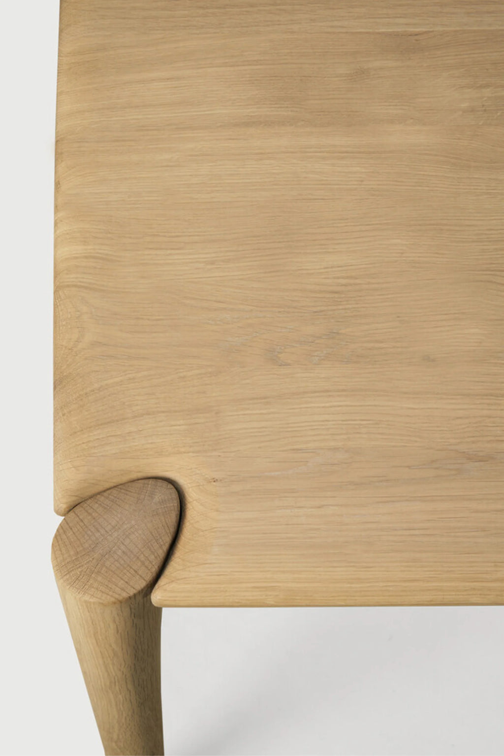 Ethnicraft PI Dining Table, a minimalist solid oak dining table crafted from light natural oak wood with a smooth finish and visible wood grain. This contemporary wooden table features an organic, rounded leg joint that seamlessly connects to the rectangular tabletop, showcasing a refined Scandinavian design. It's an ideal choice for modern dining rooms or minimalist kitchen spaces.