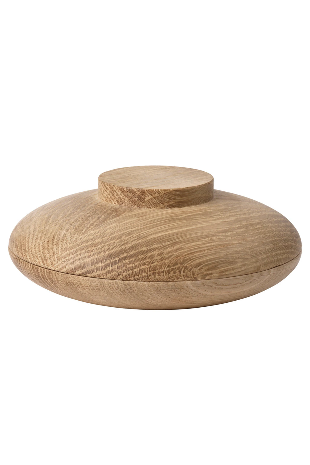 Kristina Dam Wooden Galaxy, a round decorative storage box crafted from light natural solid oak with a visible, smooth wood grain finish. This modern minimalist lidded container features a disc-shaped base, a gently domed lid, and a small cylindrical handle, embodying Scandinavian design. Perfect for organic modern shelf styling or tabletop storage in a living room, bedroom, or entryway.