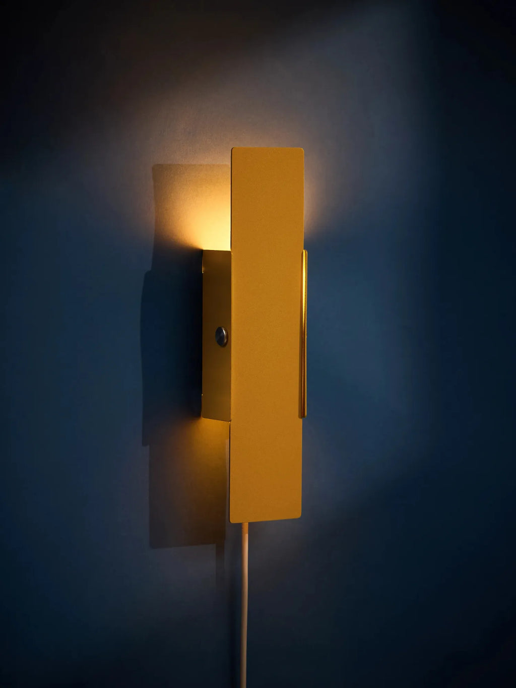 MOEBE Pivoting Wall Lamp, a sleek modern minimalist wall light featuring a rectangular matte mustard yellow metal shade that pivots to direct warm ambient light, complemented by a subtle brass-toned side accent. This contemporary wall sconce offers functional and stylish illumination, perfect as a bedside reading lamp or an accent light for Scandinavian living rooms and home offices.