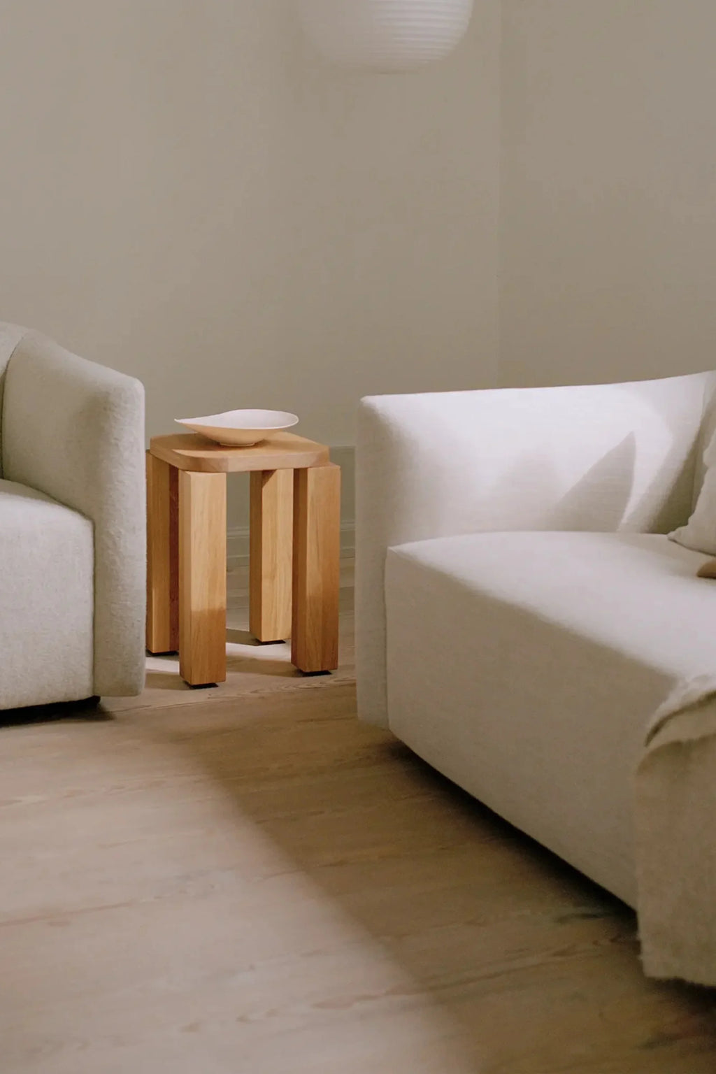 New Works Shore Sofa 2-Seater - Extended Base, a contemporary minimalist sofa featuring plush light cream bouclé fabric upholstery and gently curved, inviting armrests.