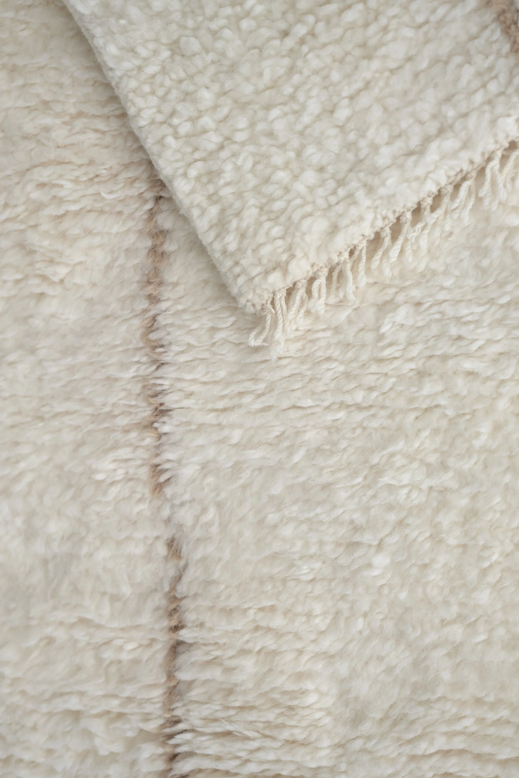 Linie Design Astral Spiral Wool Rug, a plush hand-knotted wool area rug in natural undyed cream and off-white tones, featuring a shaggy high-pile texture and subtle organic beige lines forming a gentle spiral pattern. This soft, luxurious rug is perfect for Scandinavian living rooms, minimalist bedrooms, or cozy organic modern spaces.