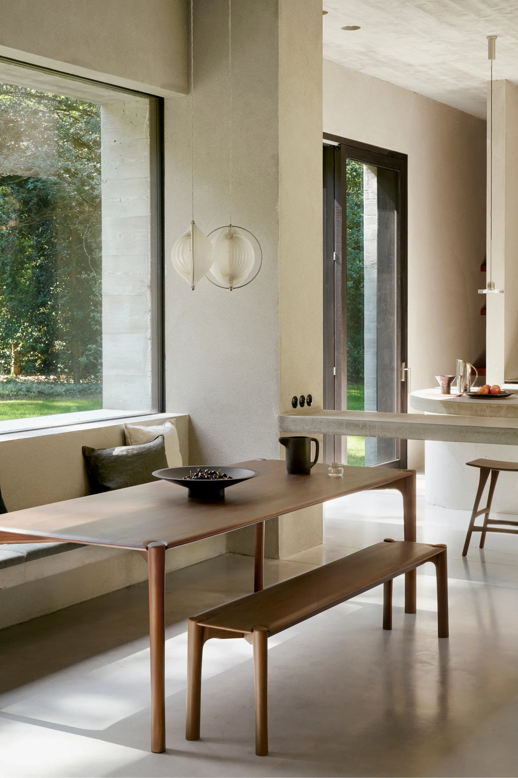 Ethnicraft PI Dining Table, a modern minimalist solid wood dining table crafted from rich dark brown wood with a smooth finish, featuring an elongated rectangular top and distinct rounded legs that seamlessly connect to the tabletop.