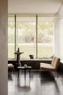 Modern interior with a large window view of greenery, featuring a chair and small table.