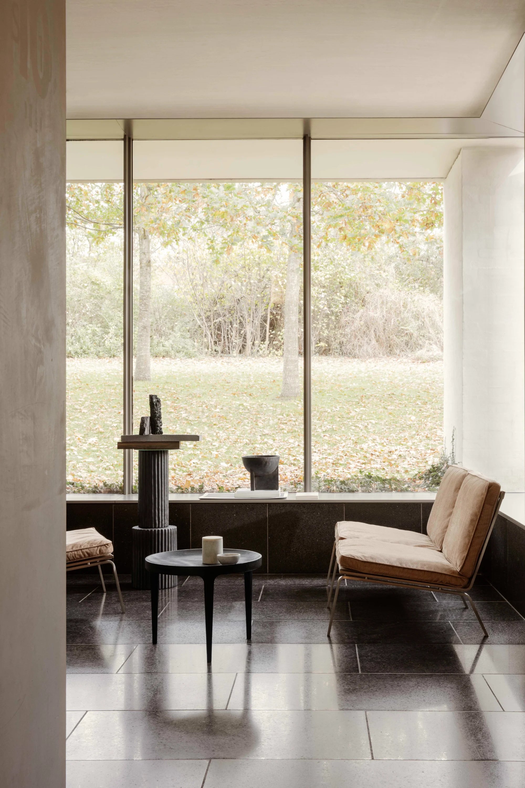 Modern interior with a large window view of greenery, featuring a chair and small table.