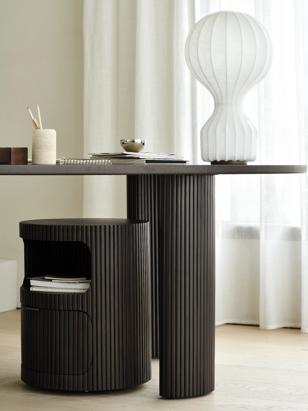 Ethnicraft Boomerang Drawer Unit, a contemporary dark brown solid wood storage unit featuring a distinctive fluted or ribbed texture around its round, cylindrical body. This organic modern cabinet offers an open curved shelf for display and a hidden drawer for discreet storage, all in a rich wenge or espresso finish. Ideal as a minimalist bedside table, a stylish home office storage solution, or a unique accent piece in a modern living room.