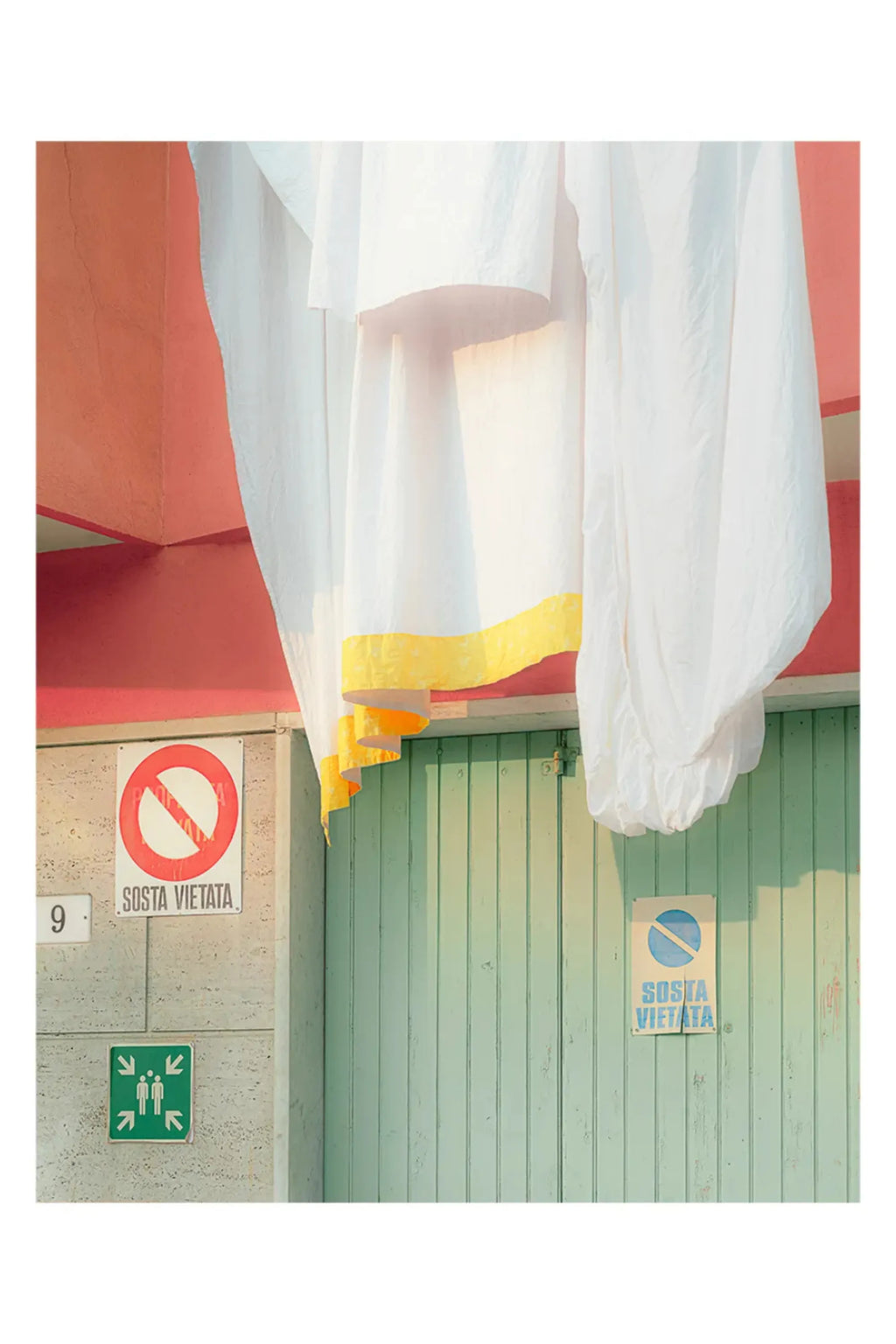 The Poster Club Camogli - Photo Art Print, a vibrant architectural photography print capturing a sun-drenched Mediterranean scene with a textured coral pink wall, weathered mint green wooden door, and soft.