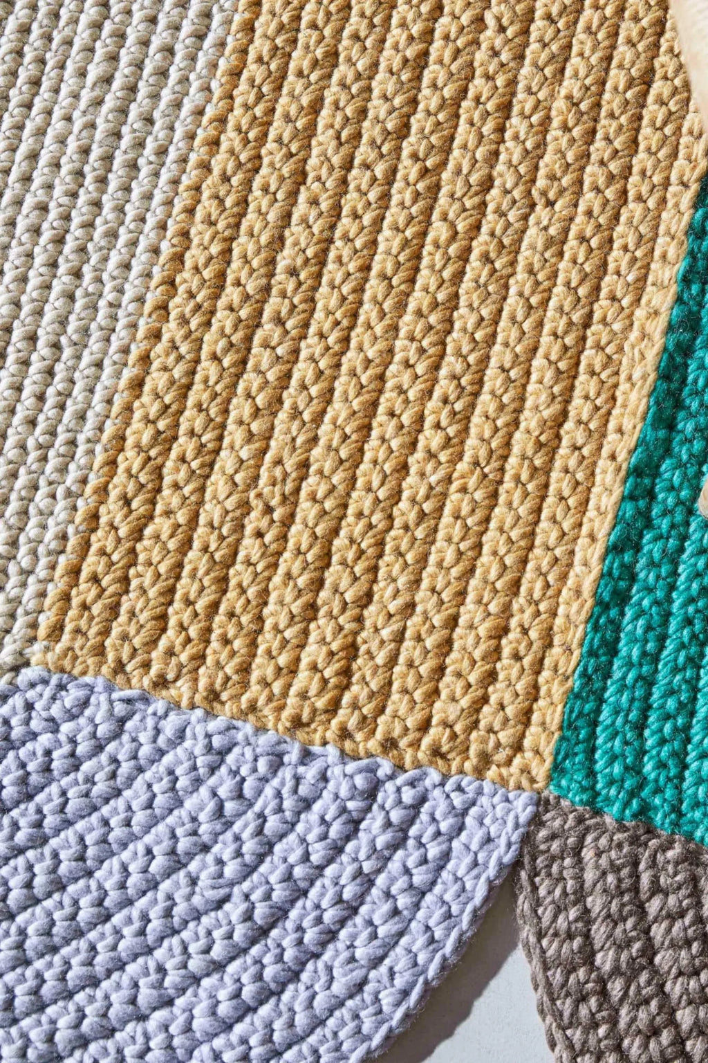 GAN Rugs Mono Beige Rug, a chunky hand-knitted natural fiber rug featuring a textured, looped weave in prominent beige tones, accented with color blocks of cream, soft grey, teal, and.
