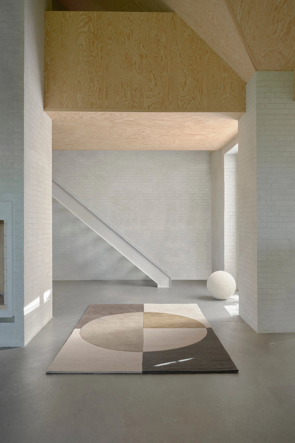 Linie Design Radiality Wool Rug, a hand-tufted area rug featuring a modern geometric pattern with a large abstract circular motif in a sophisticated palette of neutral tones, including cream, warm tan, medium grey-brown, and dark charcoal. Its plush texture and contemporary design make it perfect for adding warmth and minimalist style to modern living rooms, bedrooms, or Scandinavian-inspired interiors.
