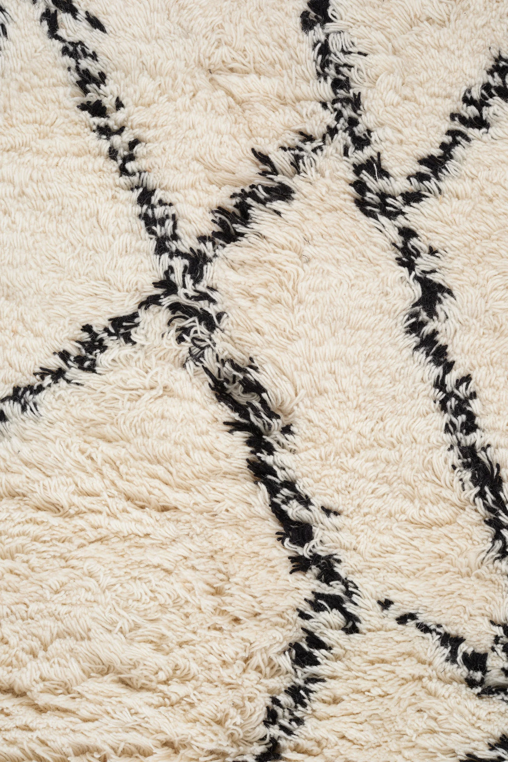 Linie Design Ruffle Wool Rug, a plush hand-knotted natural wool area rug featuring a thick cream pile with a distinctive black geometric Berber-style pattern, creating a cozy and shaggy texture. This organic modern rug is perfect for adding warmth to Scandinavian living rooms, boho bedrooms, or contemporary minimalist spaces.