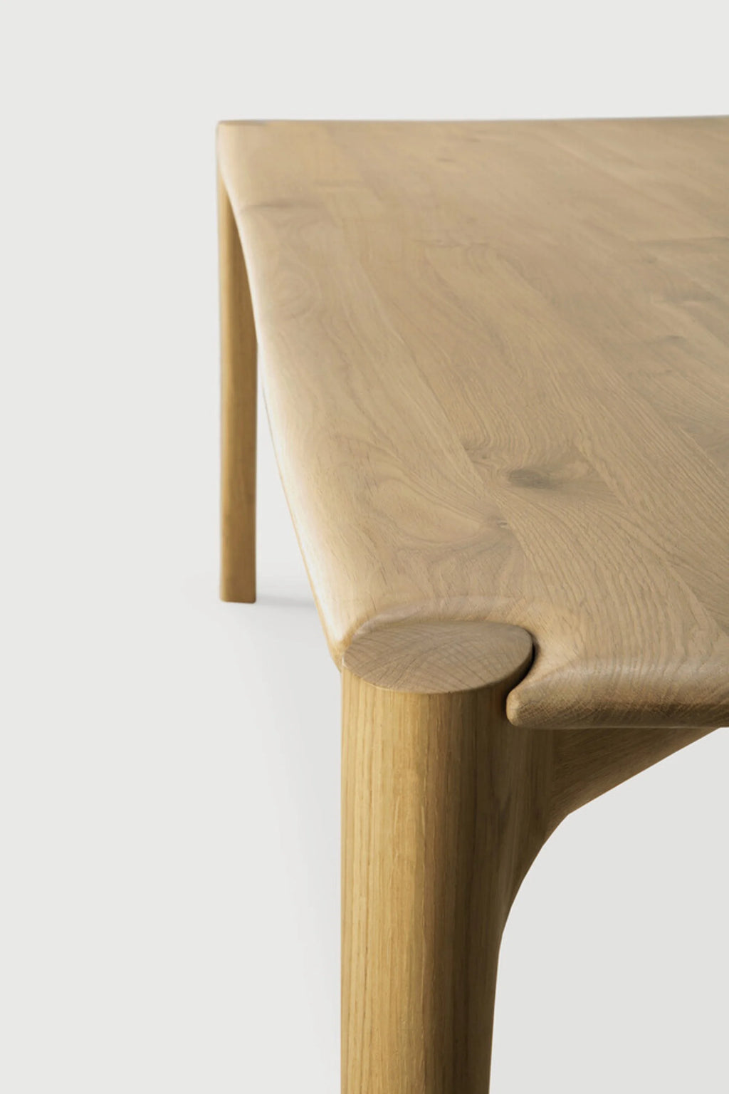 Ethnicraft PI Dining Table, a solid oak dining table with a natural light wood finish and a distinct organic modern design. It features a smooth rectangular top with gently rounded edges, seamlessly connecting to thick, rounded legs via unique, sculptural joints that highlight the natural wood grain. Perfect for creating a warm, minimalist, or Scandinavian aesthetic in contemporary dining rooms and kitchens.