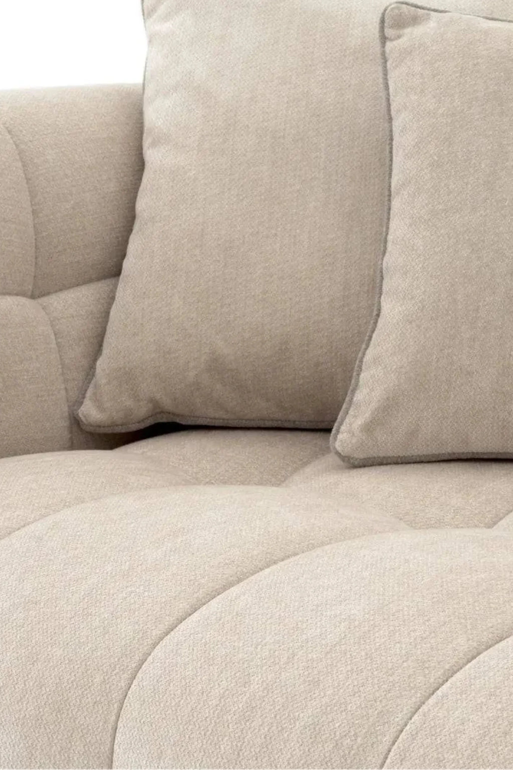 Eichholtz Breva Sofa, a luxurious contemporary sofa upholstered in a warm beige textured fabric, featuring unique channel tufting with elegant curved lines that create a soft, organic modern profile. This plush sofa includes coordinating rectangular throw pillows with subtle piping, offering sophisticated comfort for minimalist or neutral living rooms.