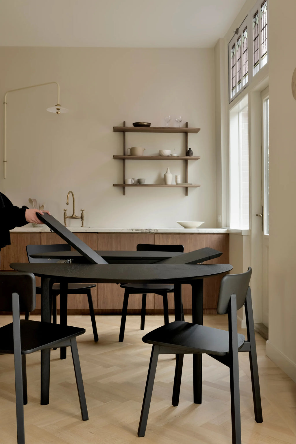 Ethnicraft Bok Extendable Dining Table, a sleek modern minimalist dining table crafted from matte black stained solid oak with a visible wood grain texture and an innovative extension mechanism shown in use.