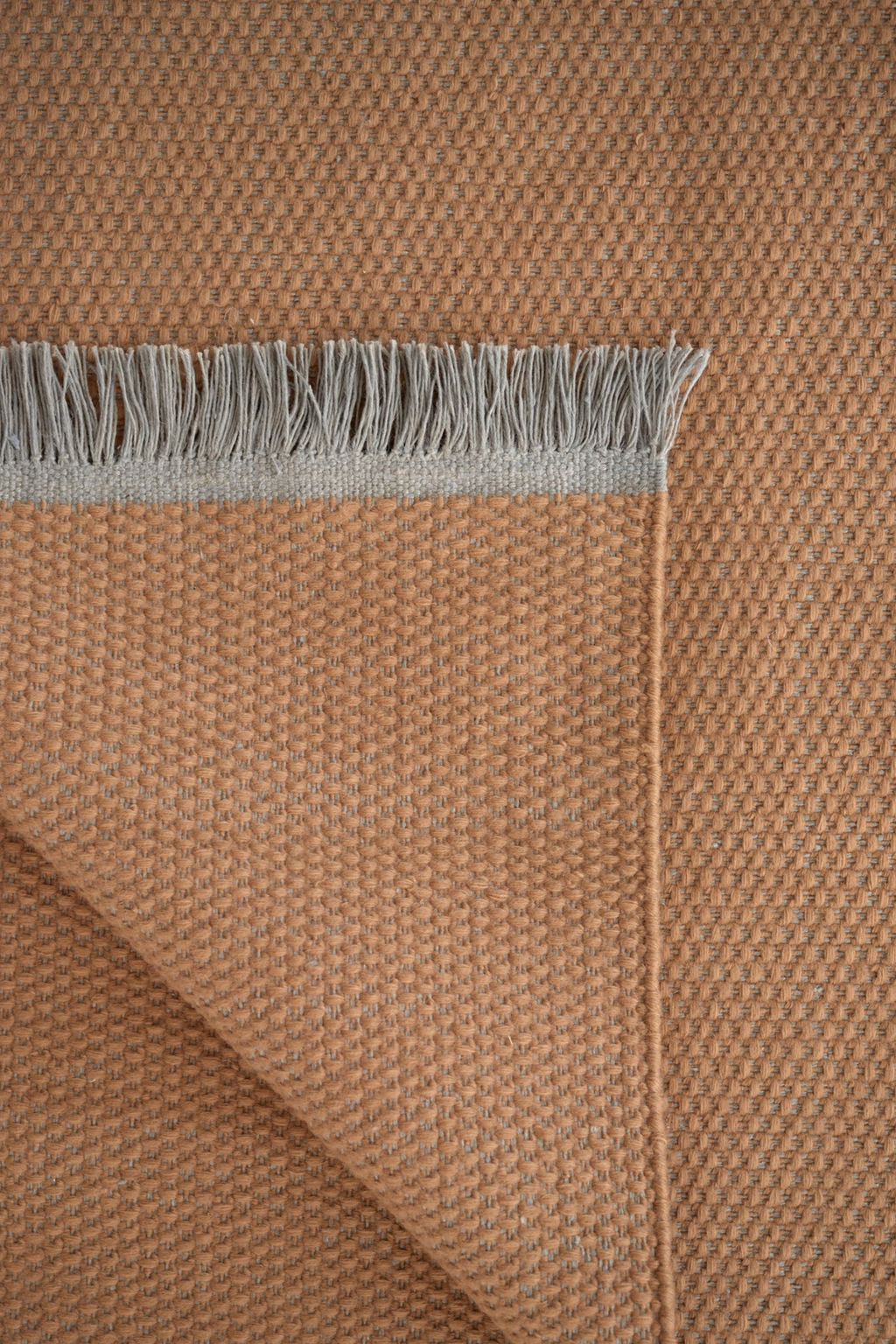 Linie Design Pastoral Unity Wool Rug, a warm terracotta hand-woven wool rug featuring a textured flat weave in a rich rust-orange hue, subtly flecked with grey, and finished with a soft.