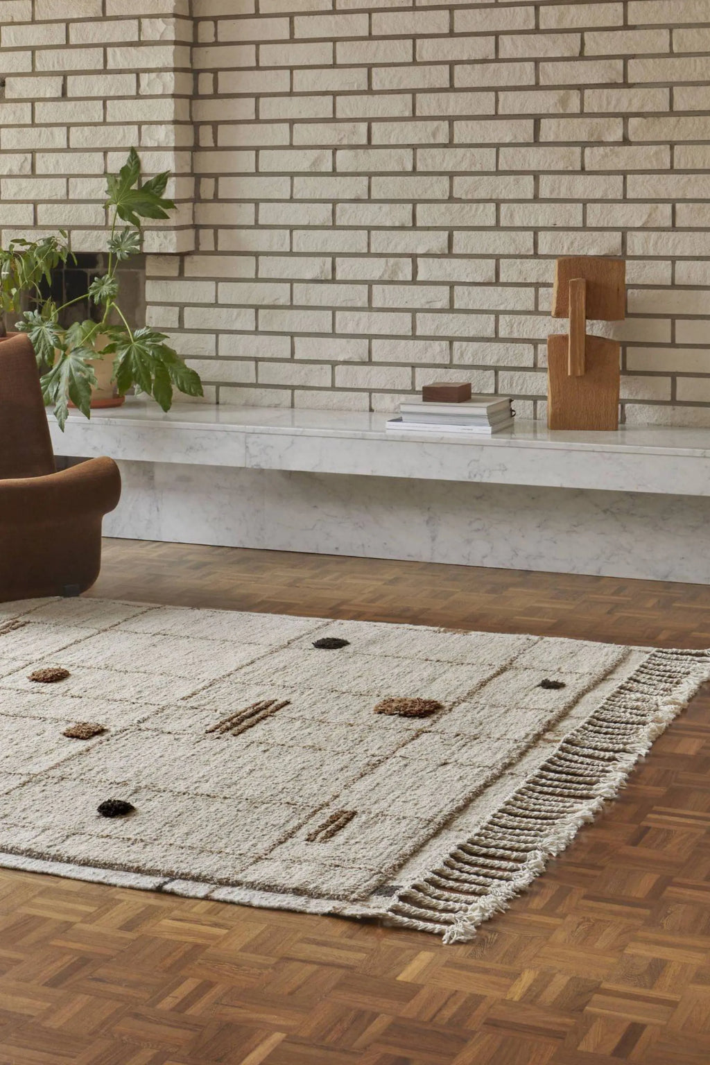 Sera Helsinki Virta Rug, a hand-knotted wool area rug featuring a plush, textured cream weave with subtle, raised brown and dark brown abstract geometric patterns. This organic modern rug has a soft, shaggy pile and a decorative fringed edge, adding handcrafted warmth. Perfect for Scandinavian living rooms, minimalist bedrooms, or cozy contemporary spaces seeking natural texture.