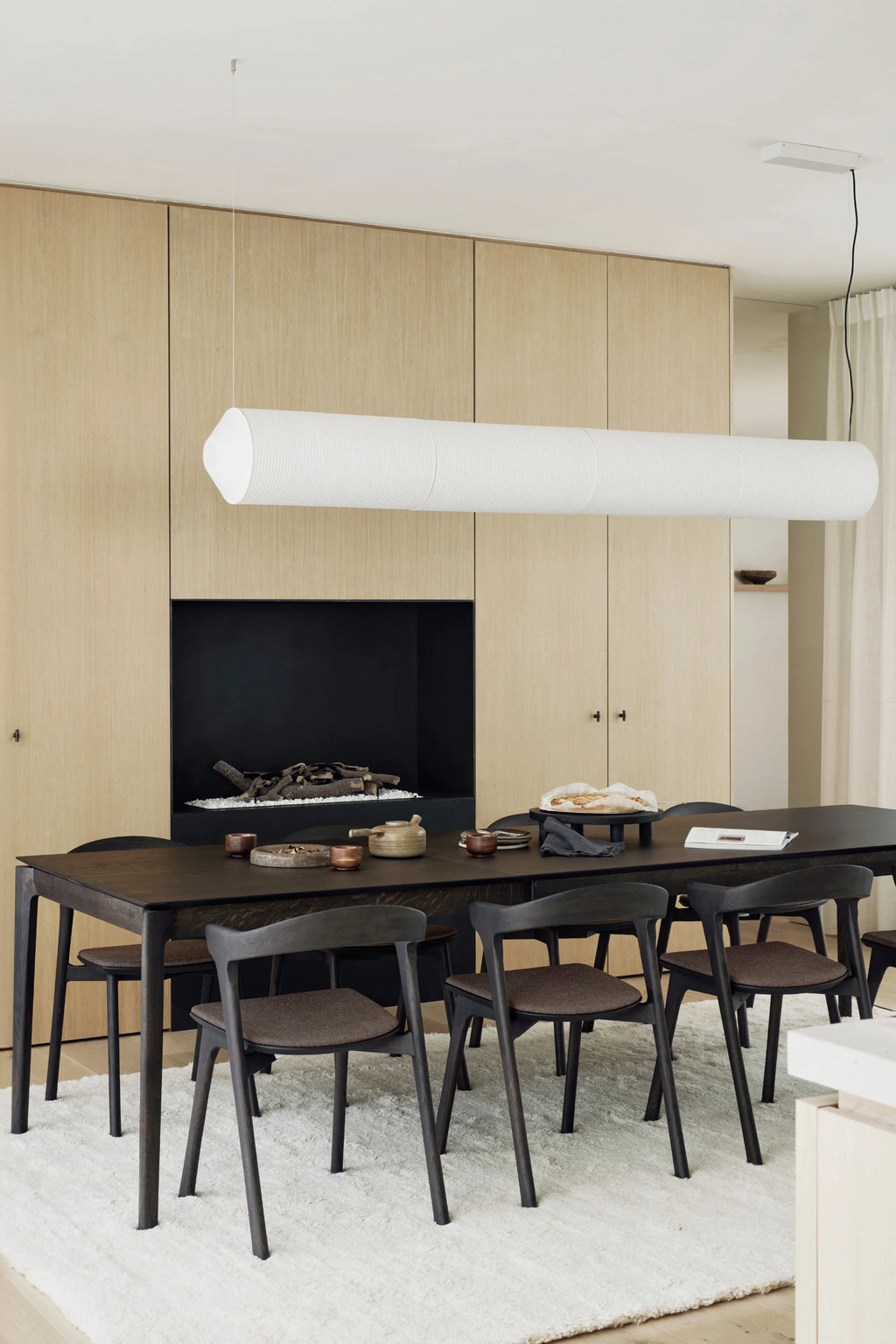 Ethnicraft Bok Extendable Dining Table, crafted from solid black stained oak wood with a smooth finish and elegant, subtly rounded edges on its rectangular top and tapered legs. This modern minimalist dining table offers a timeless design, perfect for contemporary dining rooms, Scandinavian interiors, or large family gatherings.
