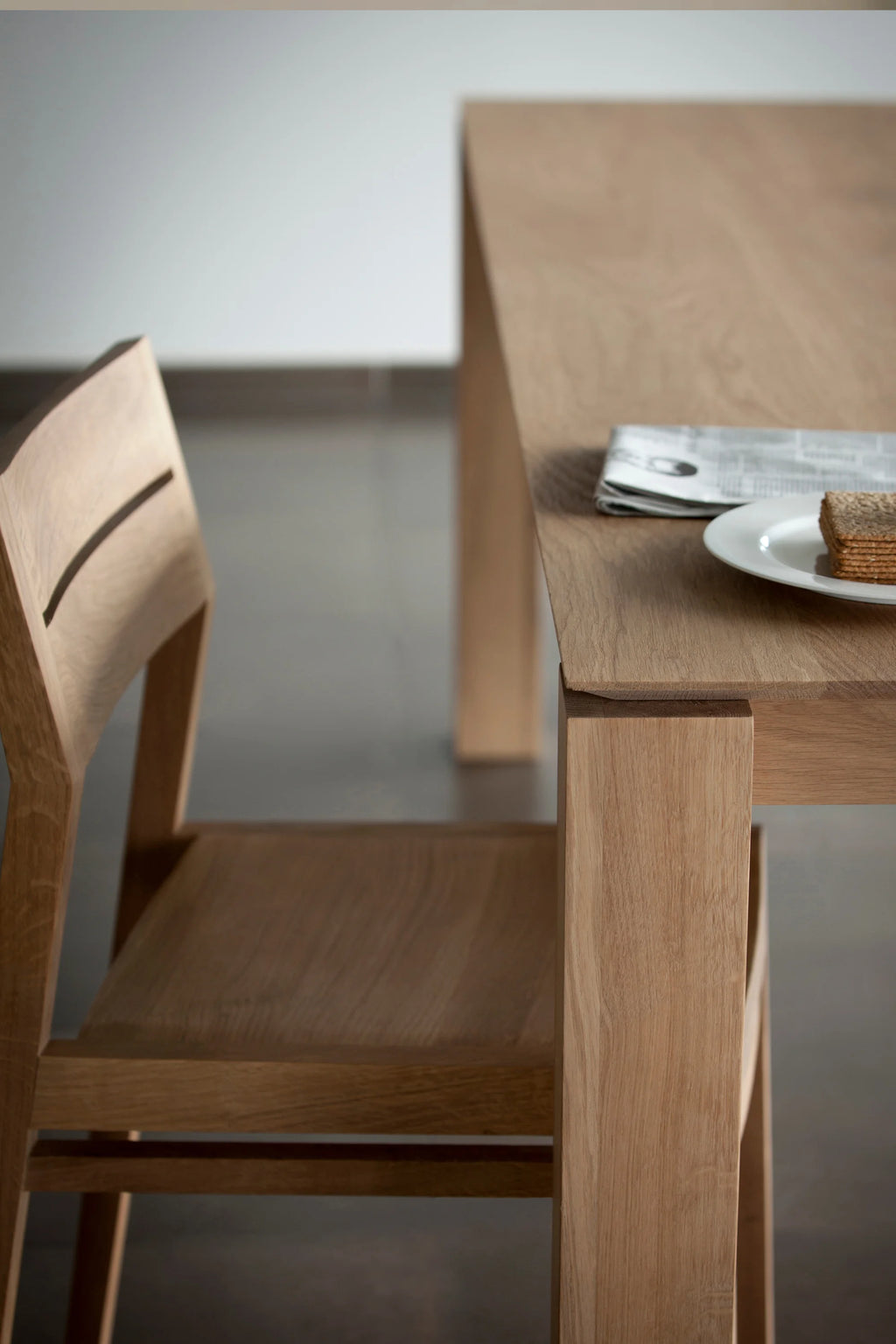 Ethnicraft Slice Dining Table, a modern minimalist solid oak dining table featuring a natural light oak finish and a clean, rectangular silhouette. Its sturdy design includes thick, straight legs and a smooth wood grain top, perfect for Scandinavian dining rooms or contemporary kitchens.