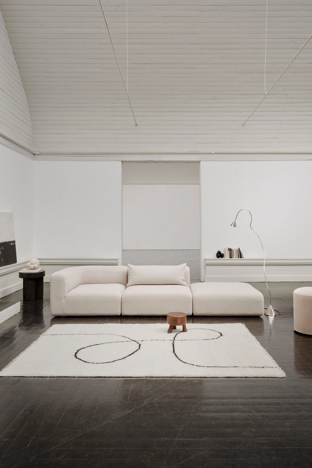 Linie Design Astral Spiral Wool Rug, a plush hand-tufted wool area rug in a soft cream color with an abstract black spiral design. Its high pile texture and organic graphic pattern create a striking modern minimalist statement piece. Perfect for contemporary living rooms, Japandi-inspired bedrooms, or stylish entryways.
